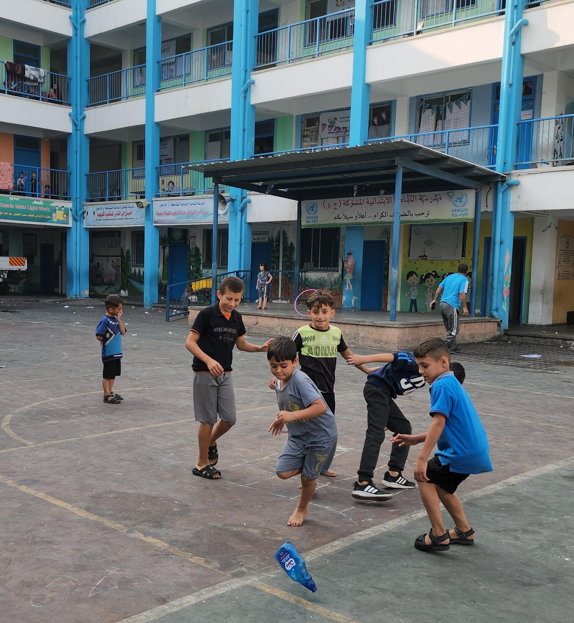 © UNICEF/UNI452828/Islyeh At a UNRWA school playground in the Gaza Strip, children play while families seek refuge from ongoing airstrikes.