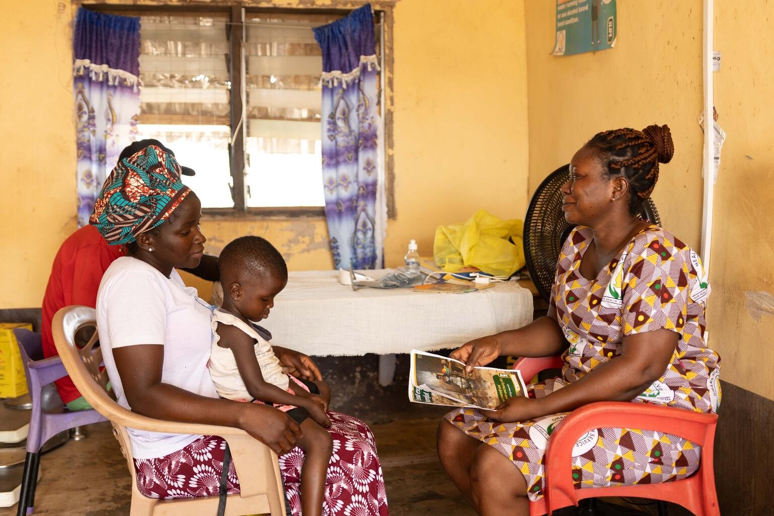 © UNICEF/UNI788173/Adams Agness, a mother in Sangbaa, and her husband speak with the community midwife Sophia at a community health center.